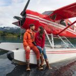 Couple sits on the float of Rust's Flying service red De Havilland Beaver