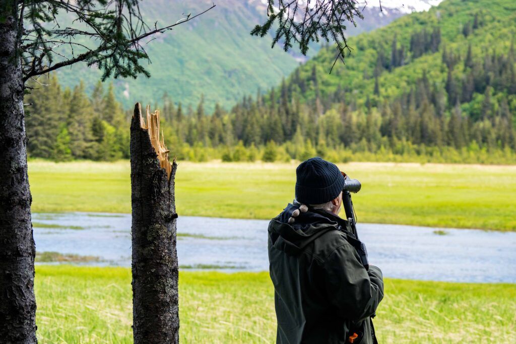 man with binoculars looks for bears at Chinitna Bay Alaska